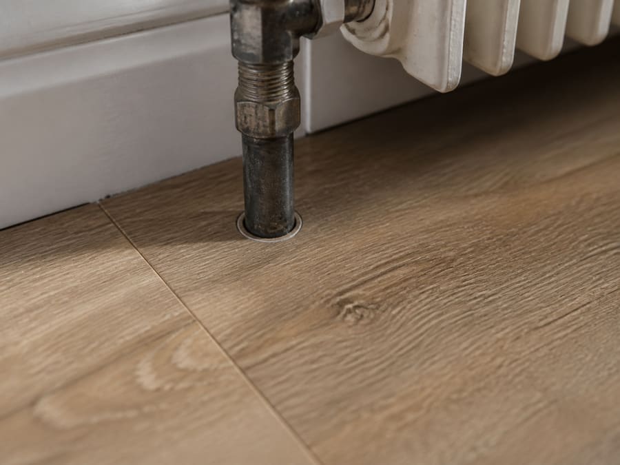 Luxury vinyl plank being laid in a kitchen with cabinetry visible behind